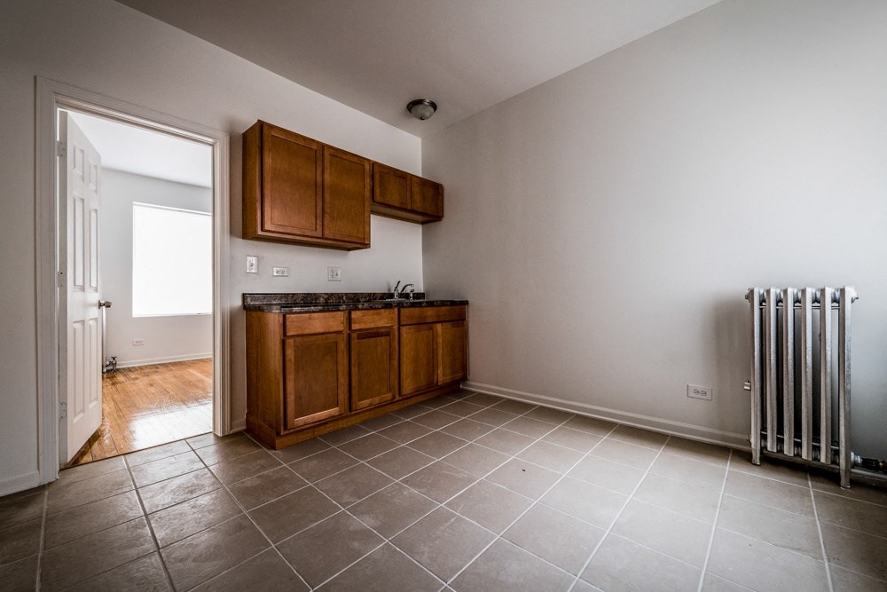 an empty kitchen with wooden cabinets and a radiator