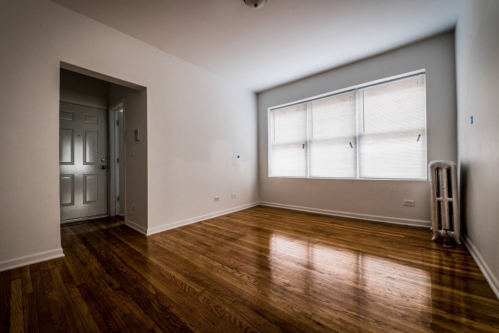 an empty living room with wood floors and a window