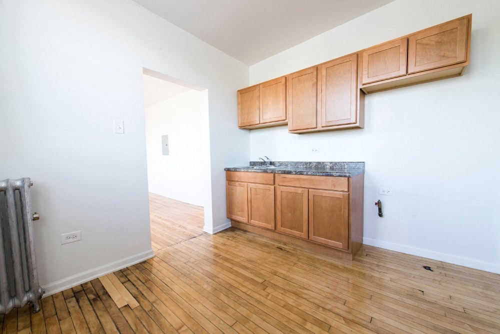 an empty room with wood flooring and wooden cabinets
