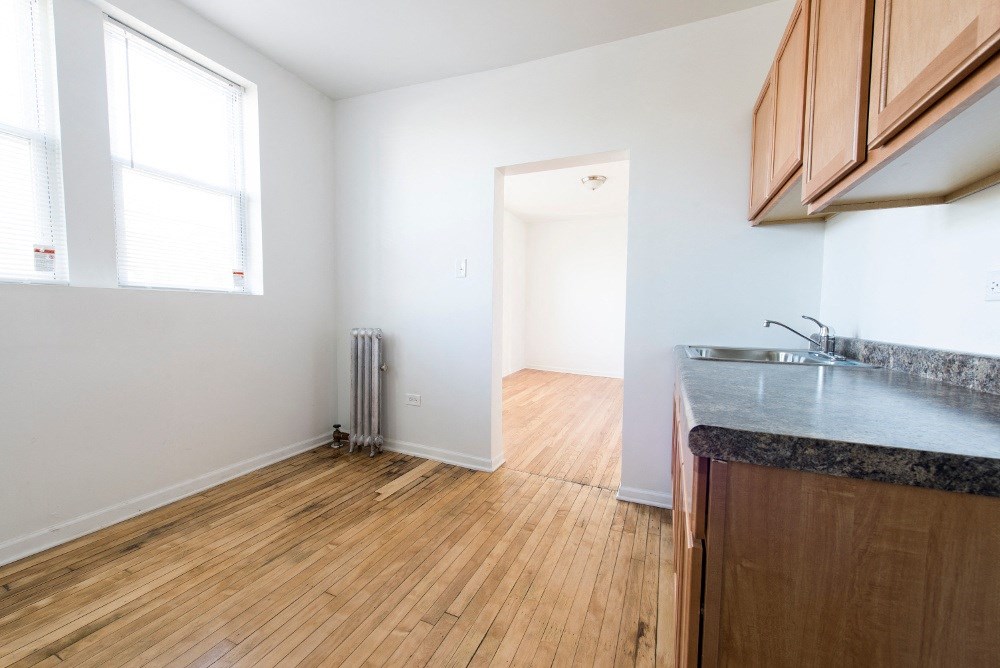 an empty kitchen and living room with wood flooring and a window