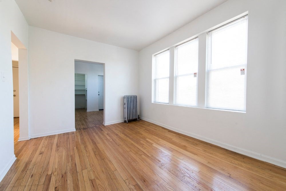 an empty living room with a wood floor and three windows