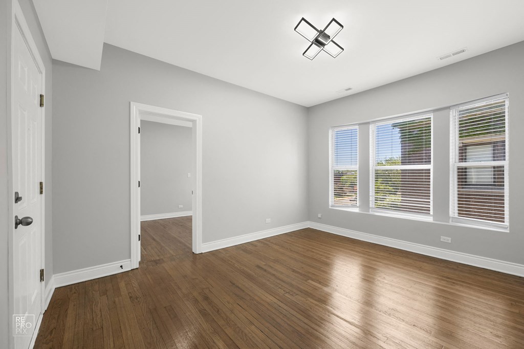 an empty living room with wood floors and a ceiling fan