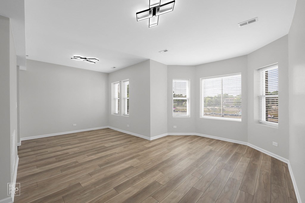 an empty room with hardwood floors and a chandelier