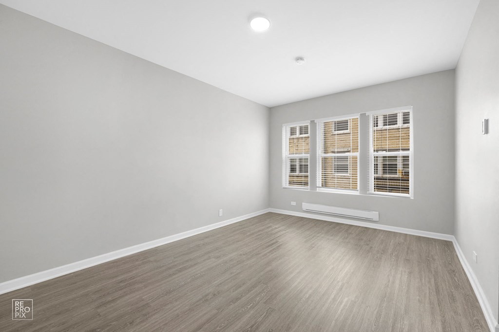 a bedroom with gray walls and hardwood floors