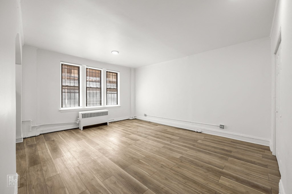 a living room with white walls and wood floors and a window