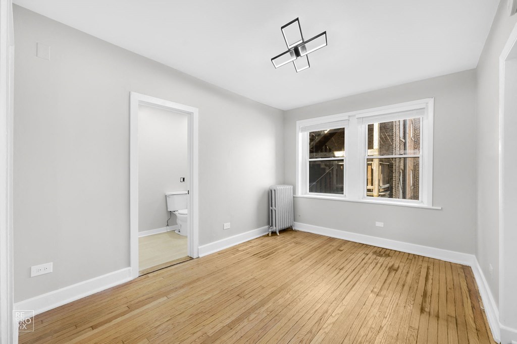 a bedroom with a large window and hardwood floors