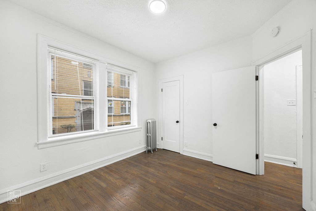 an empty living room with two windows and a door