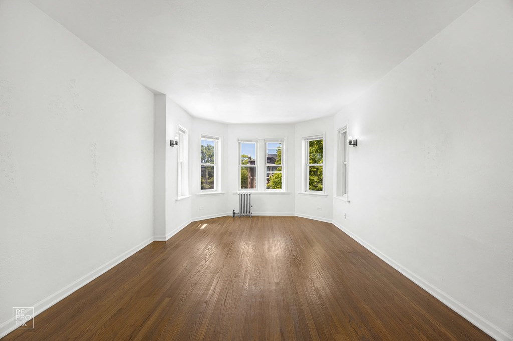a living room with white walls and wood floors and a window