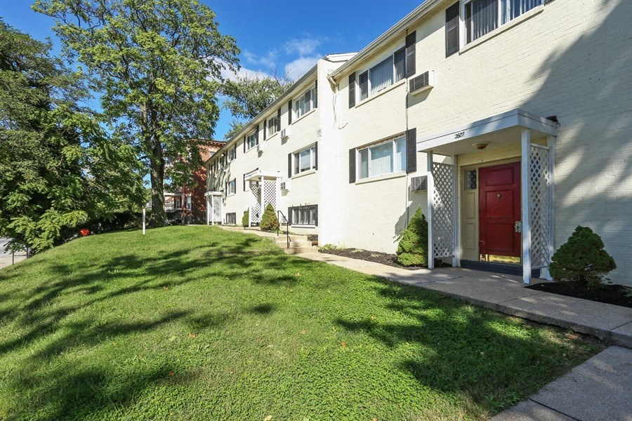 the exterior of a white apartment building with a red door