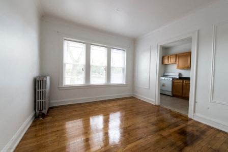 a empty living room with a wood floor and three windows
