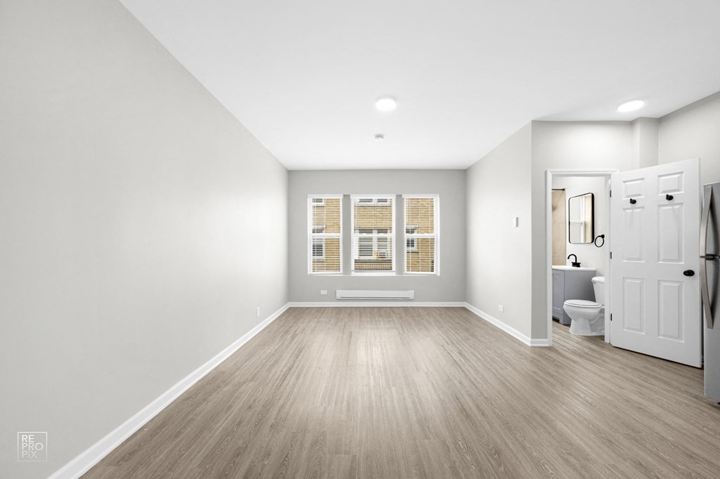 a bedroom with a medium sized window and hardwood floors