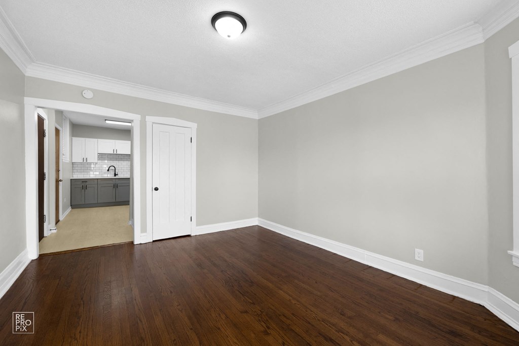 a bedroom with hardwood floors and grey walls
