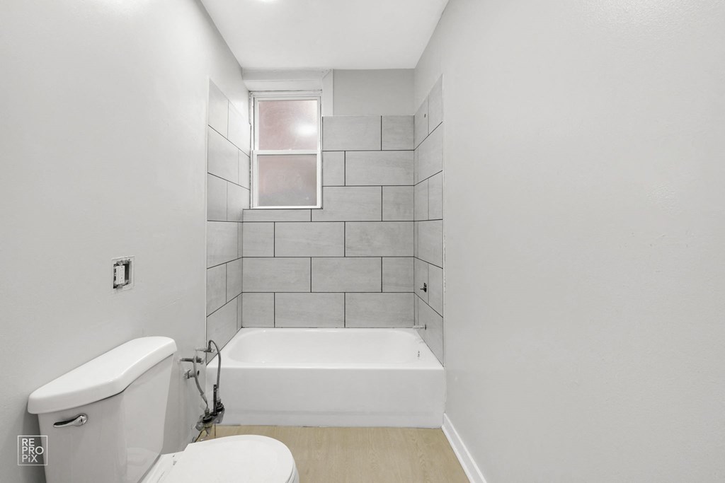 a bathroom with white walls and a white bathtub