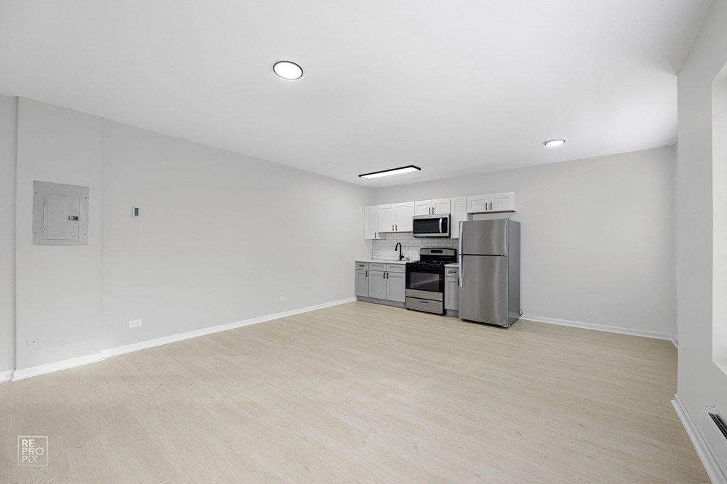 a bedroom with a medium sized bed and a kitchen with stainless steel appliances