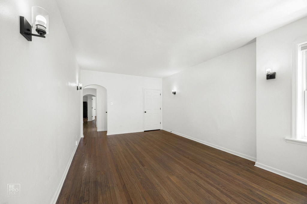 an empty living room with white walls and wood floors