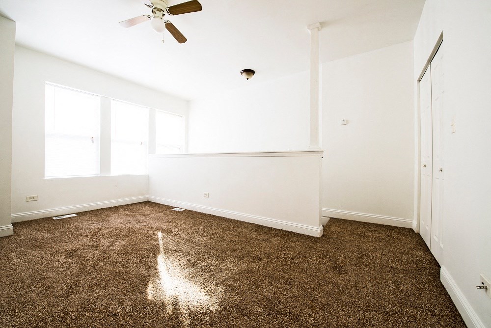 an empty room with carpet and a ceiling fan