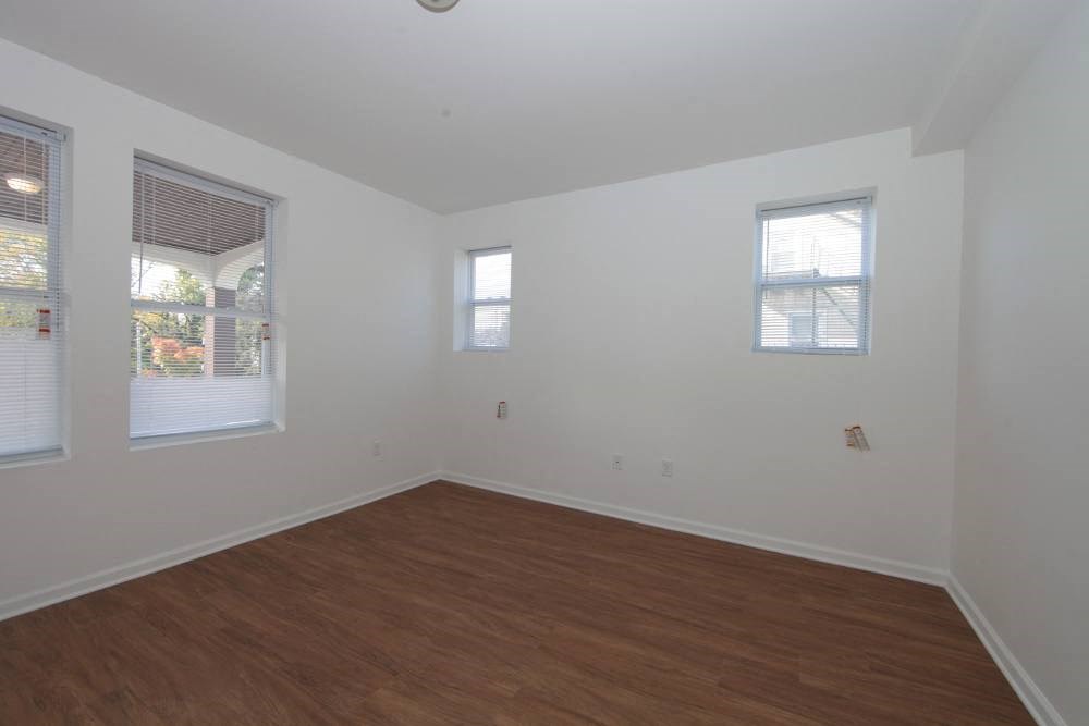an empty room with a wooden floor and three windows