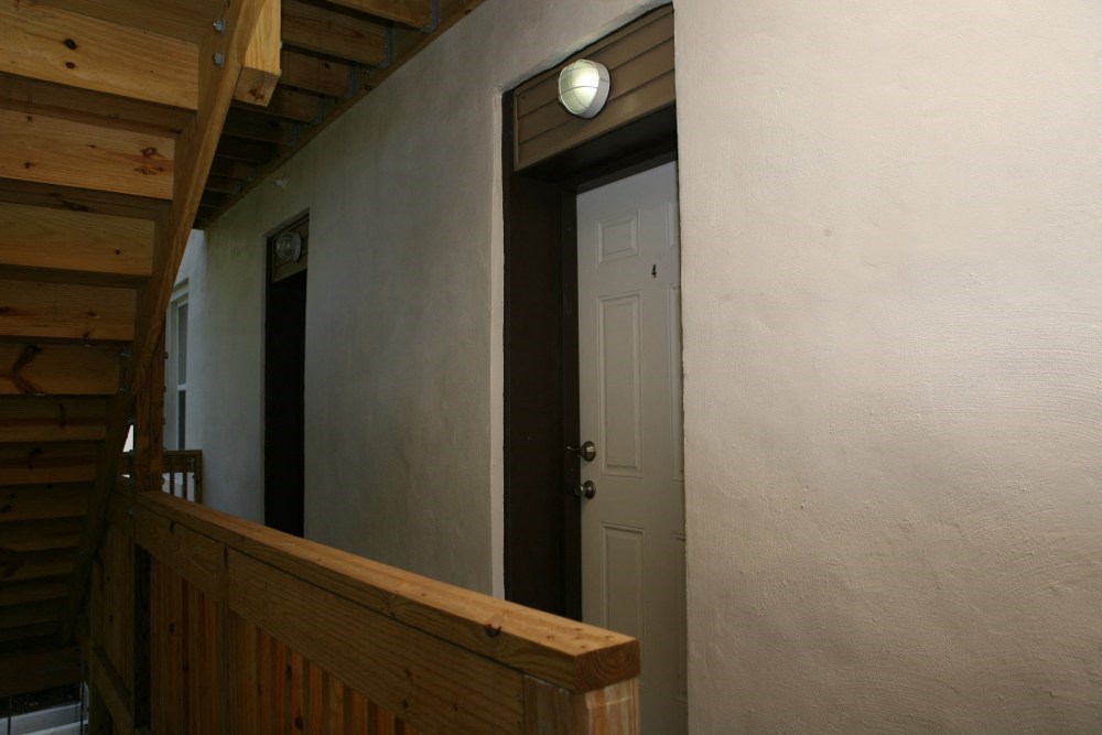 a stairwell with a wooden railing and a white door