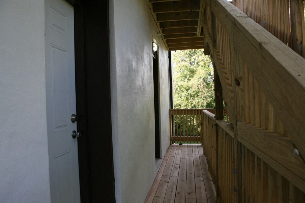 a view of a porch with wooden floors and a white door