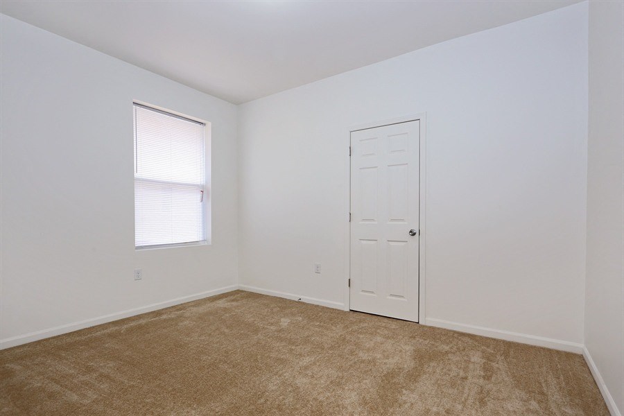 an empty room with a white door and a window and a carpet