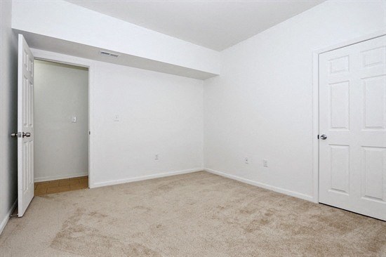 an empty bedroom with a door to a closet