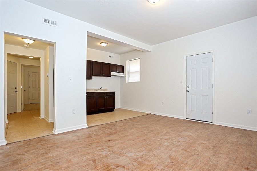 an empty living room and kitchen with a white door
