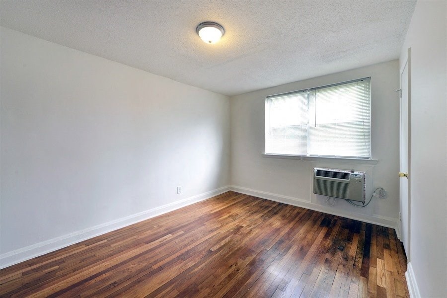 an empty living room with wood floors and a window