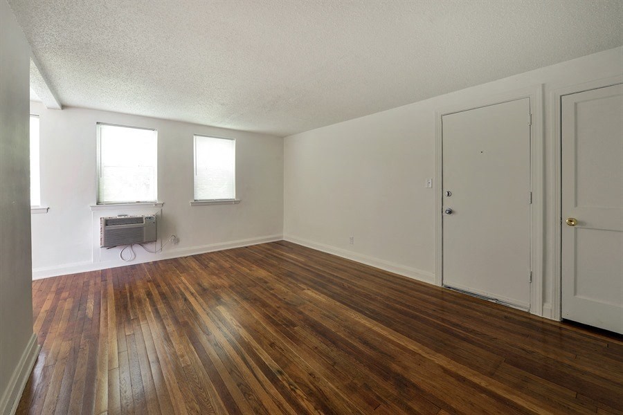 an empty living room with wood floors and white walls