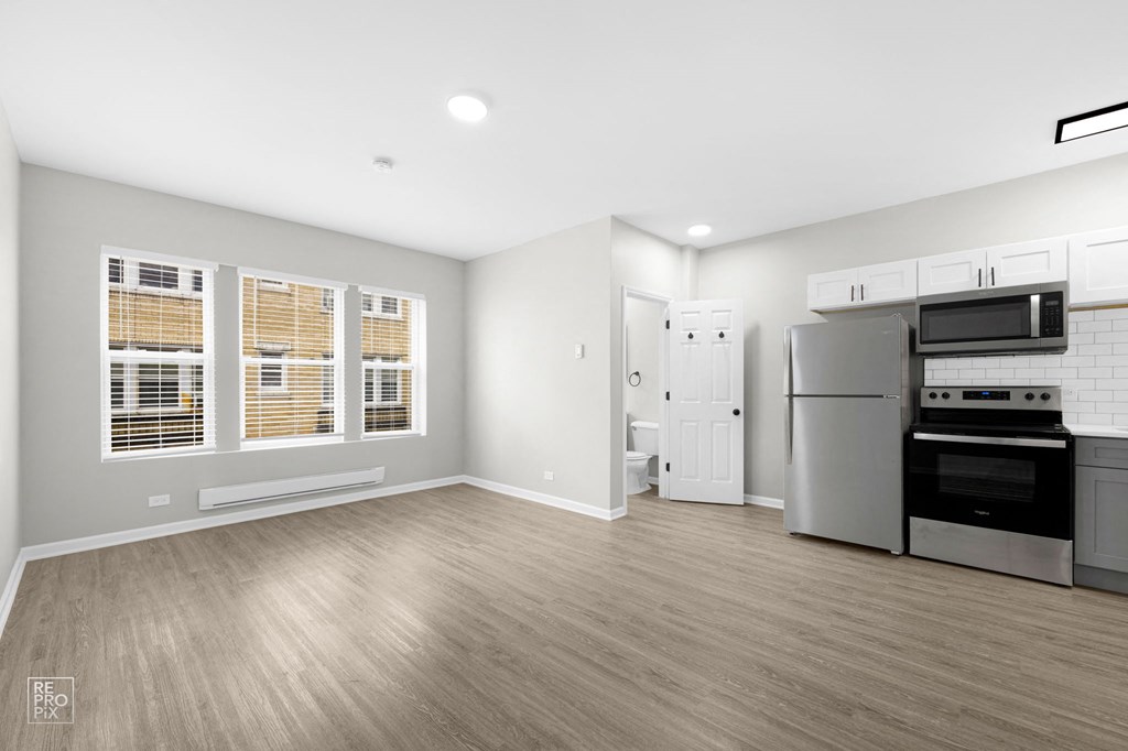 a kitchen and living room with hardwood floors and grey walls