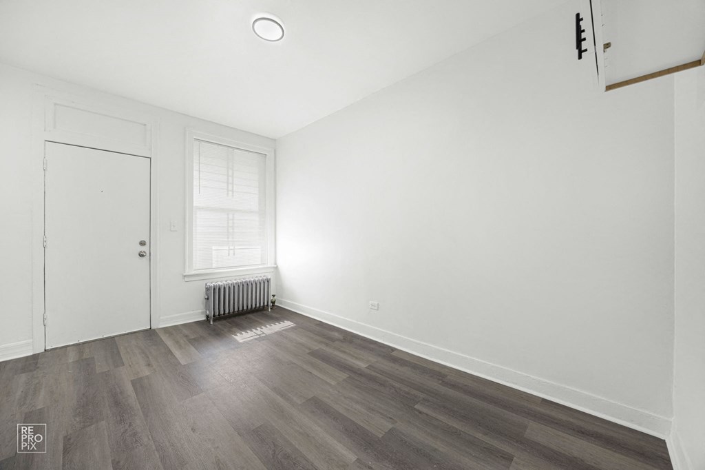 a living room with white walls and a window and wooden floors