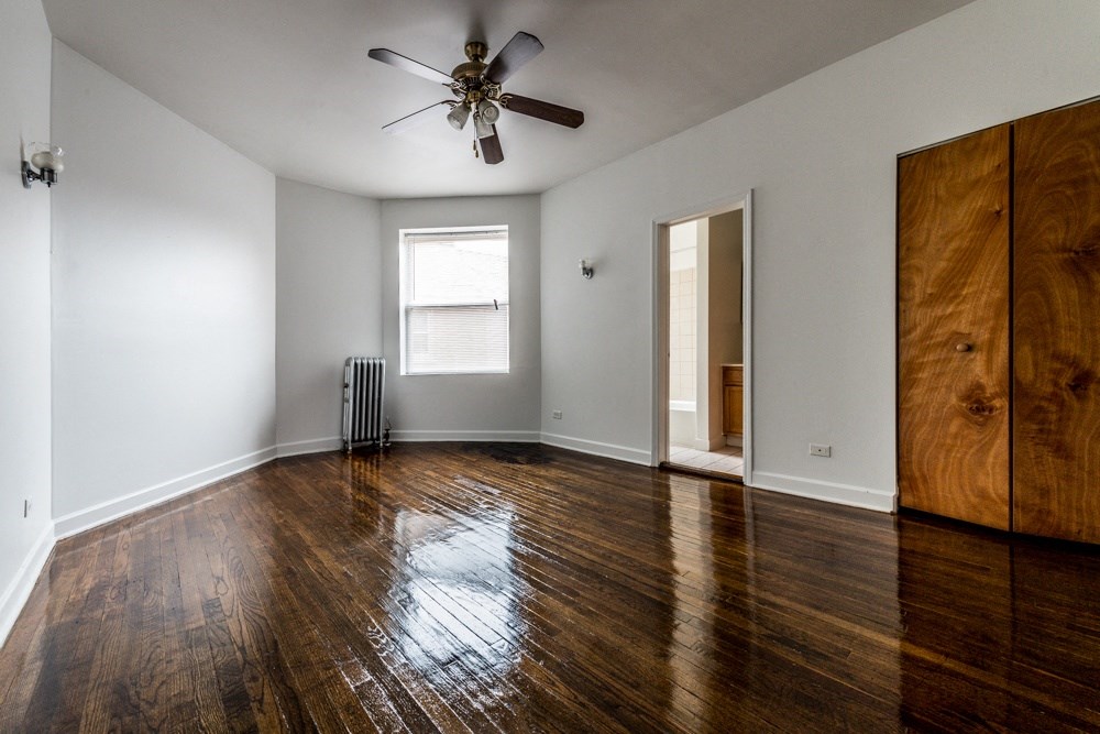 an empty living room with wooden floors and a ceiling fan