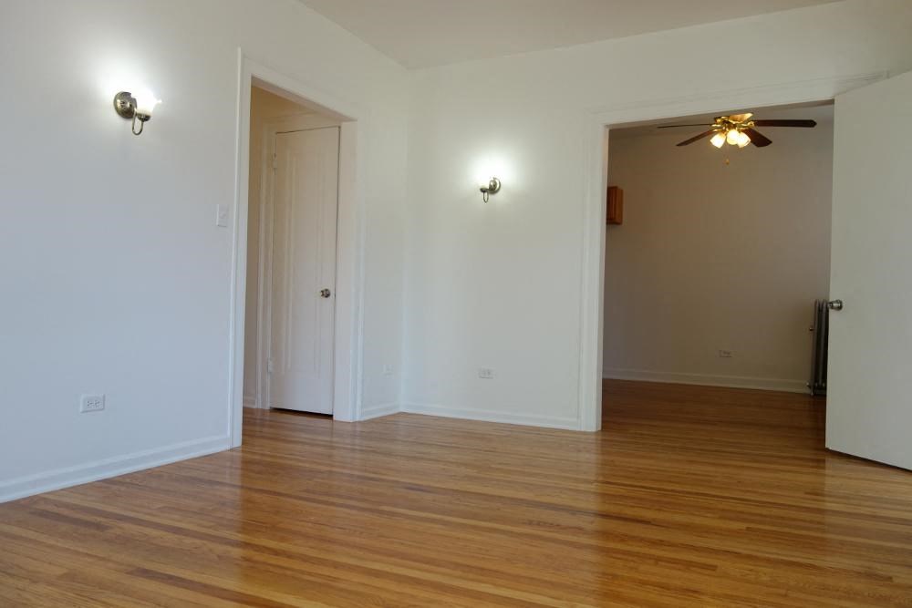 an empty living room with wood floors and a ceiling fan