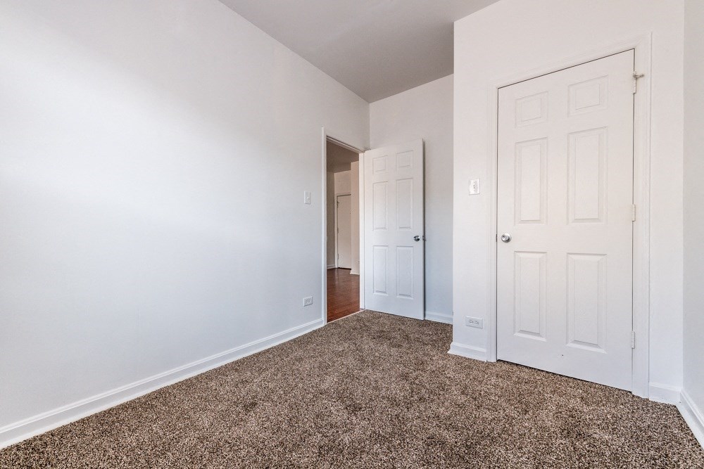 a bedroom with a carpeted floor and a white door