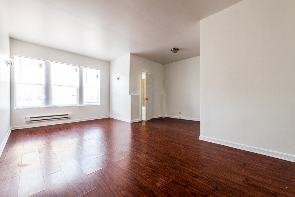 an empty living room with wood floors and white walls