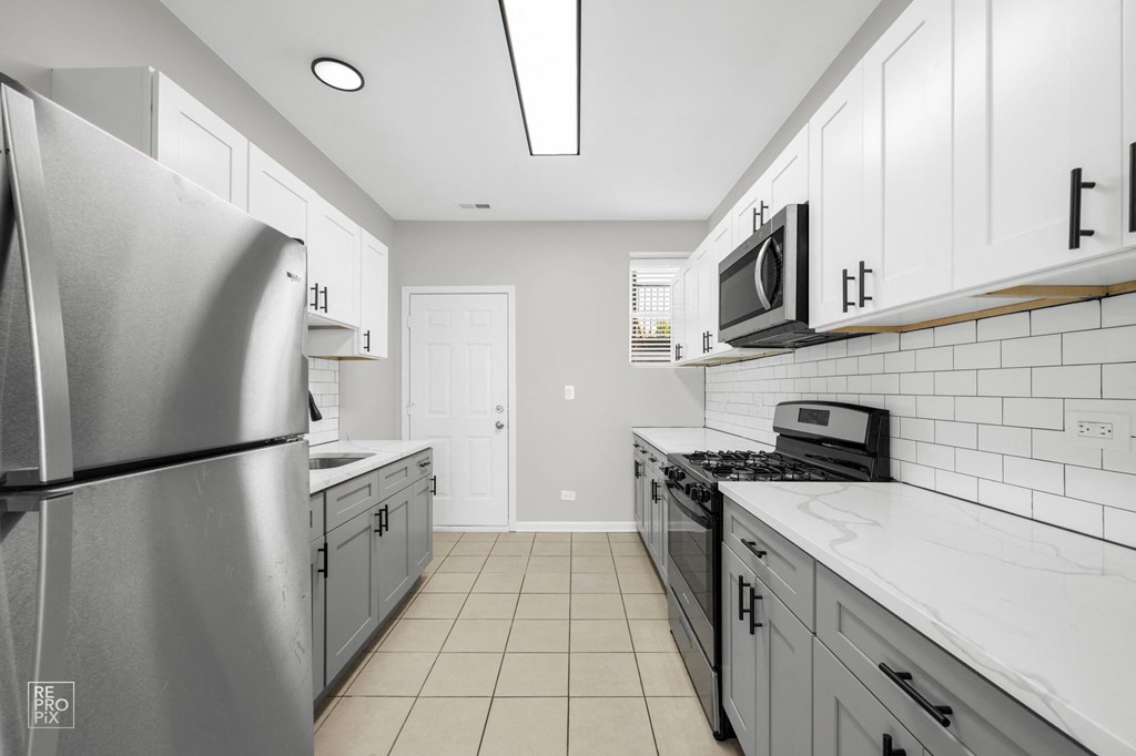 a kitchen with white cabinets and a white tile floor