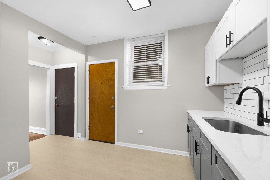 a kitchen with white countertops and gray walls