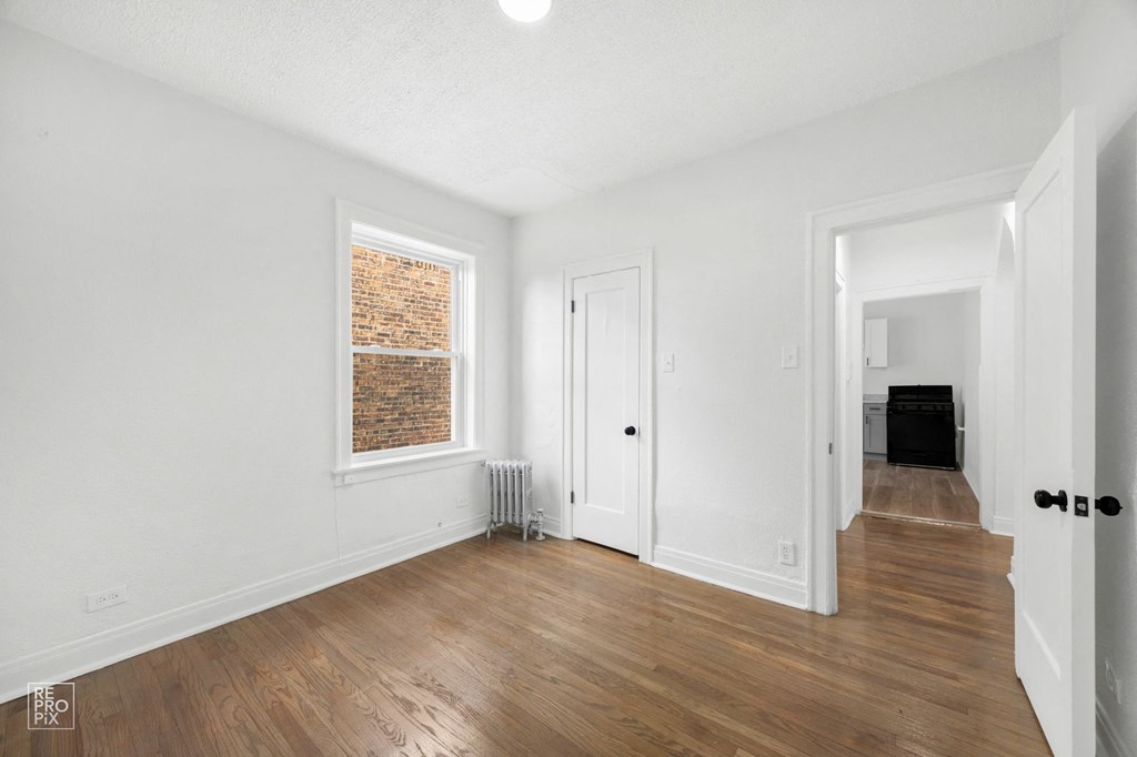 an empty living room with white walls and wood flooring