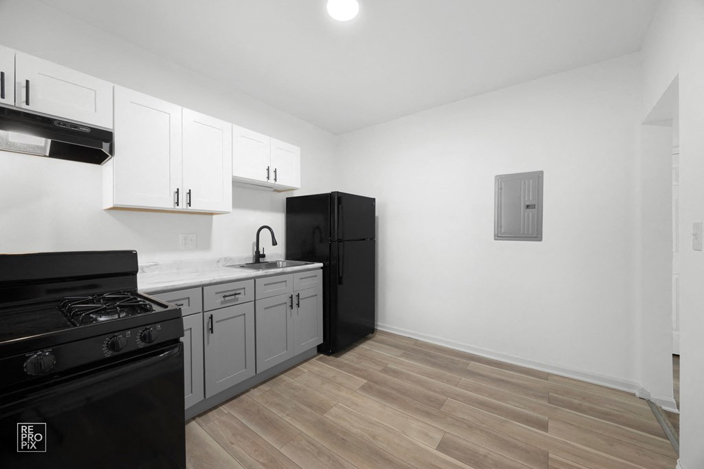 a kitchen with white cabinets and black appliances and a black refrigerator