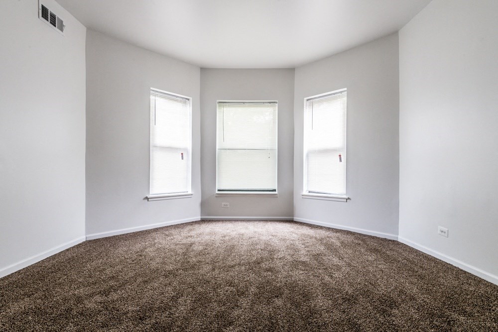 an empty room with three windows and a carpet