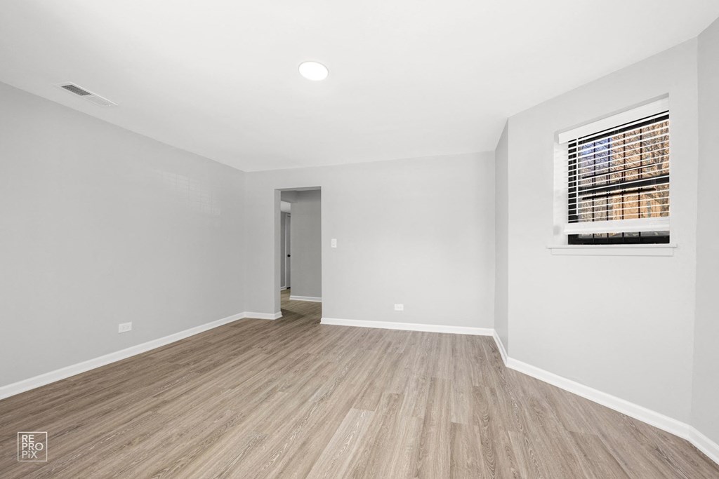 a spacious living room with white walls and hardwood floors