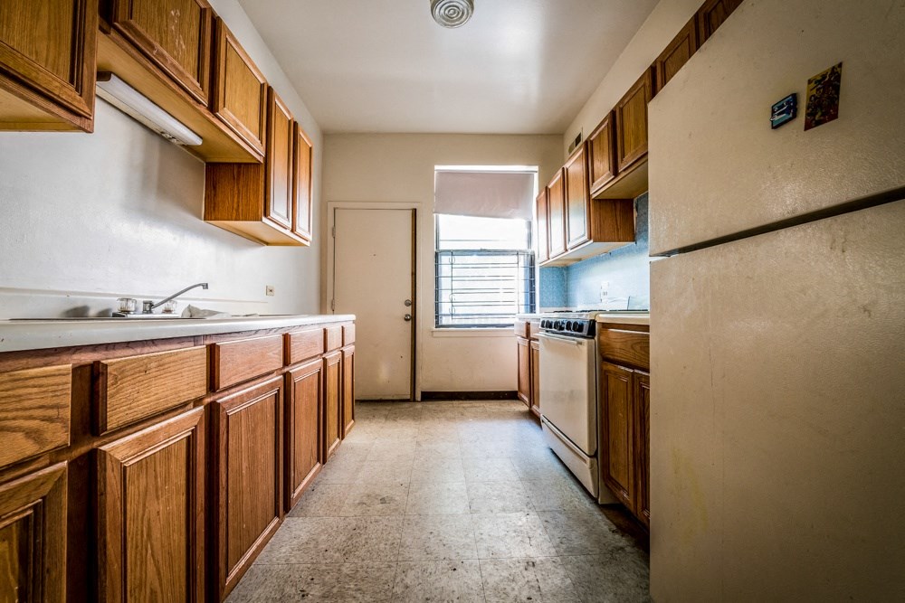 a kitchen with wooden cabinets and a refrigerator and a sink