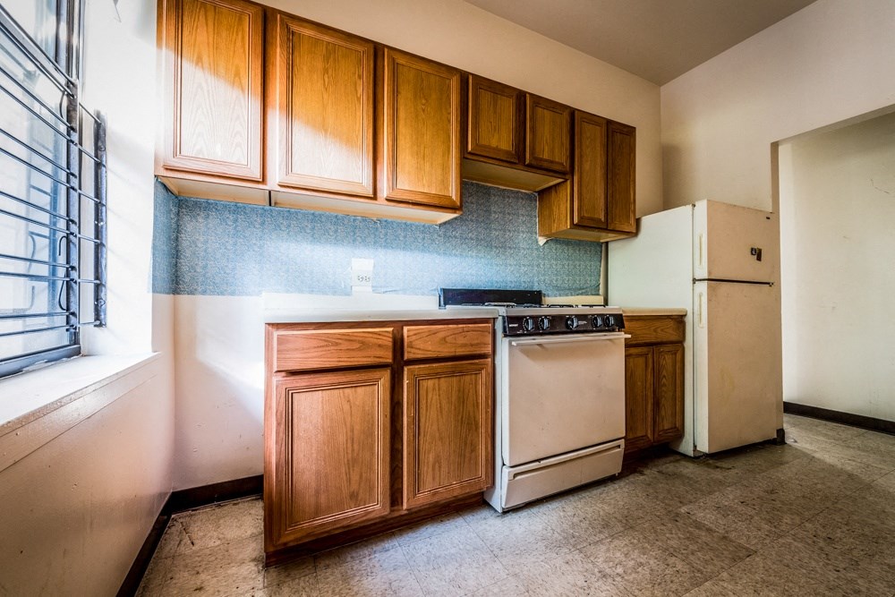 an empty kitchen with white appliances and wooden cabinets