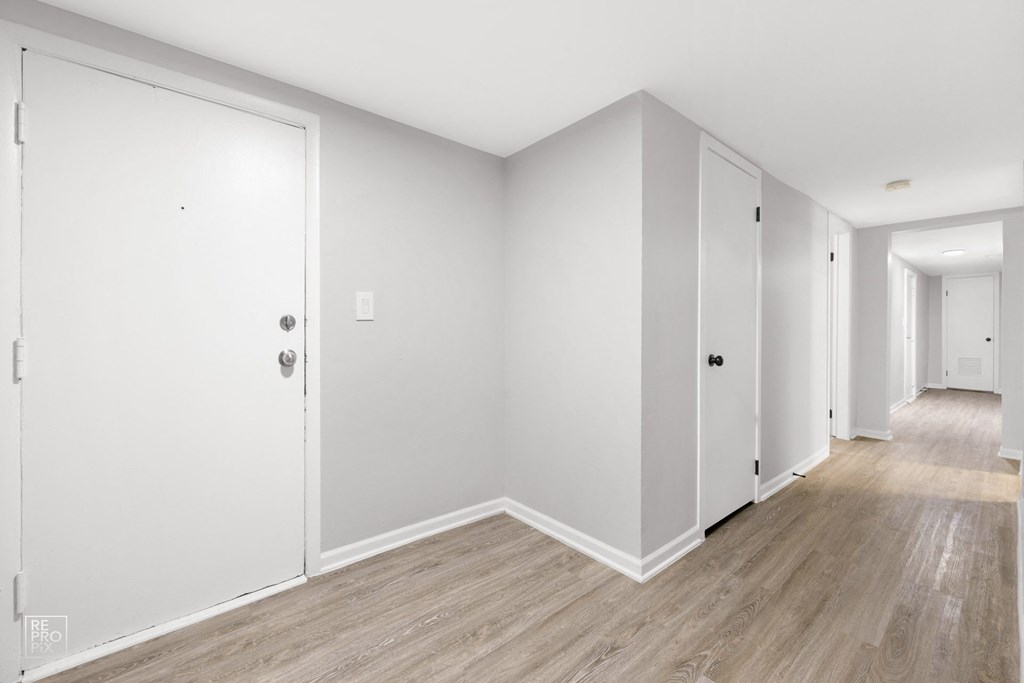 a bedroom with hardwood floors and white walls