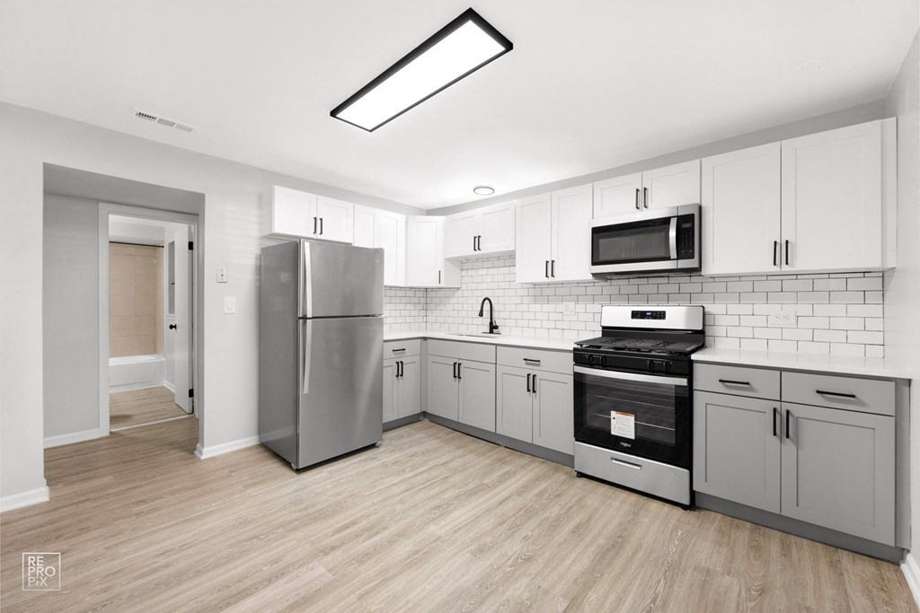 a kitchen with white cabinets and stainless steel appliances
