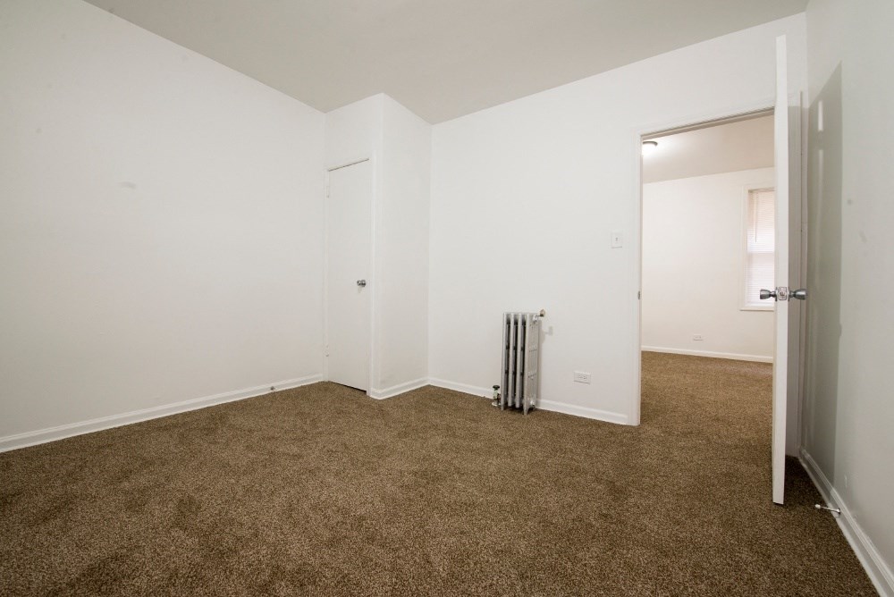 an empty living room with carpet and a door to a closet