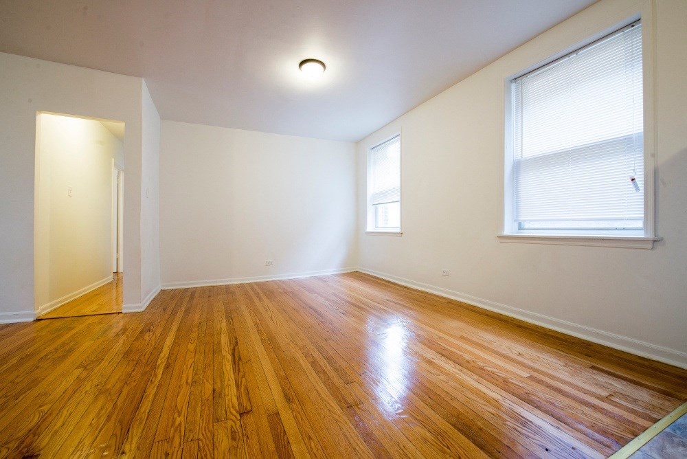 an empty living room with wood floors and a window