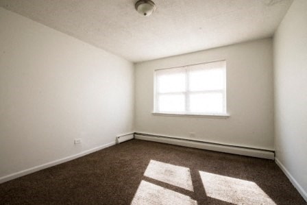 an empty room with a window and a carpet