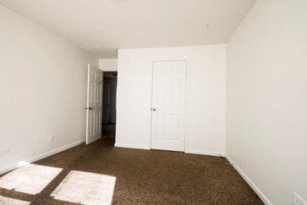 a room with a white door and a brown carpet