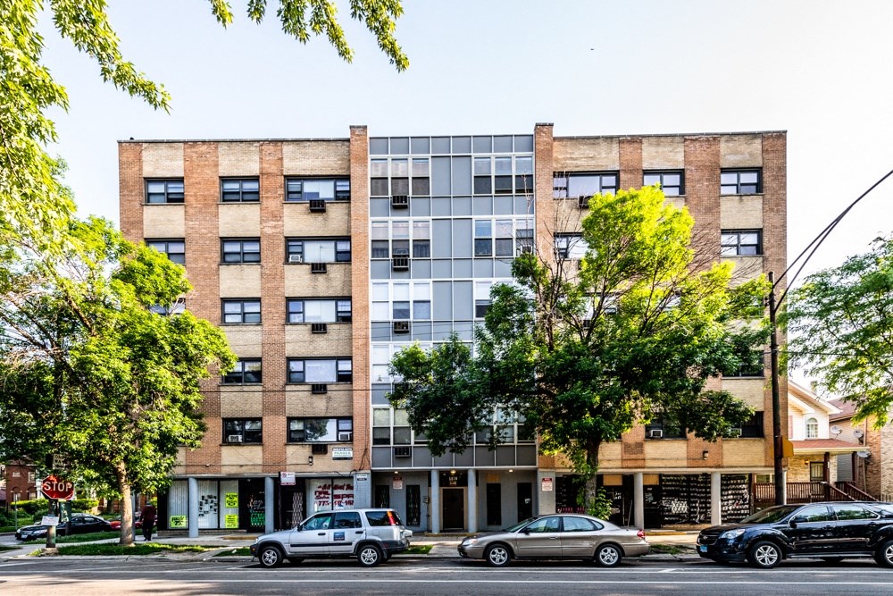 an apartment building on a city street with cars parked in front of it