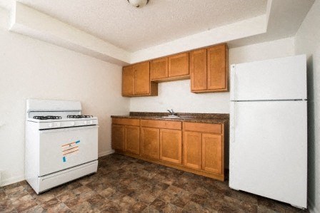 an empty kitchen with white appliances and wooden cabinets